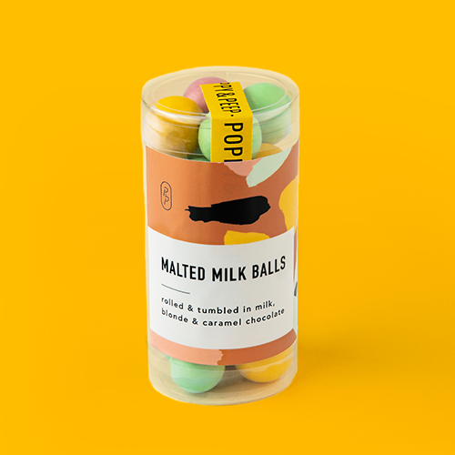 A clear cylindrical container with colorful malted milk balls covered in milk and white chocolate, branded 'Malted Milk Balls'